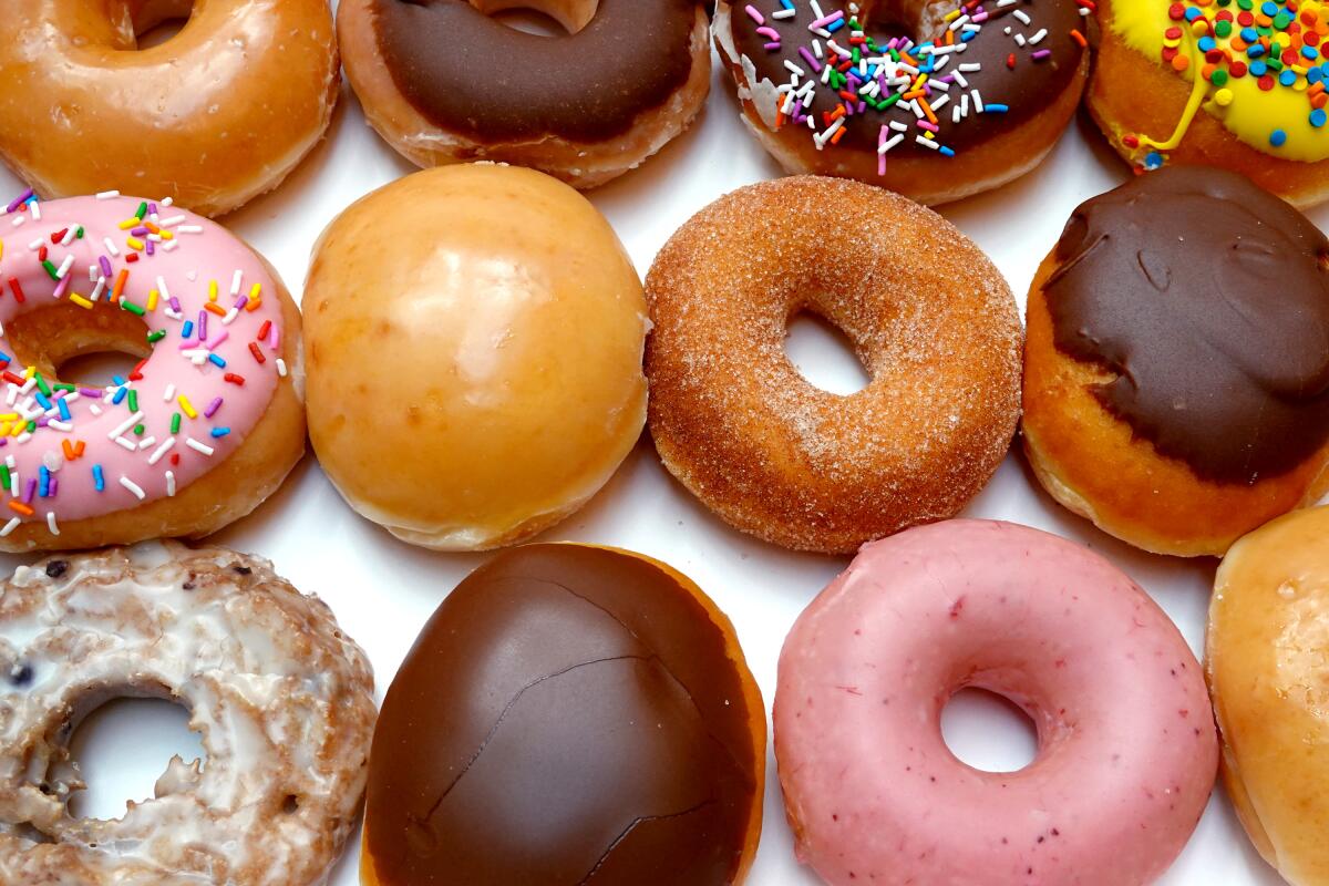 An assortment of doughnuts, including pink frosted ones and chocolate glazed ones