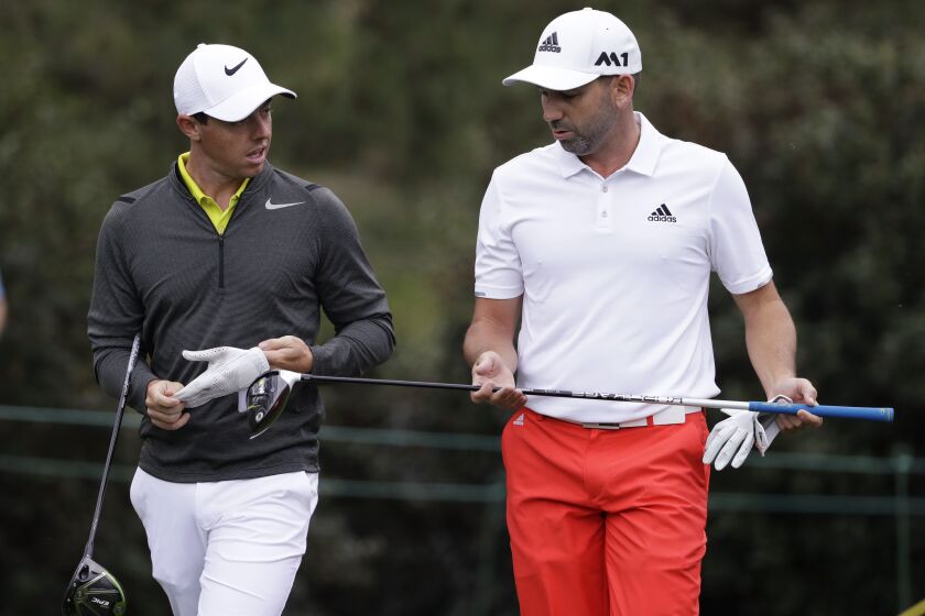 FILE - Rory McIlroy, left, of Northern Ireland, and Sergio Garcia, of Spain, walk up the 15th fairway during a practice round for the Masters golf tournament April 5, 2017, in Augusta, Ga. McIlroy, in a lengthy interview in the Sunday Independent in Ireland, says his close friendship with Garcia ended over a testy text exchange at the U.S. Open. (AP Photo/Matt Slocum, File)