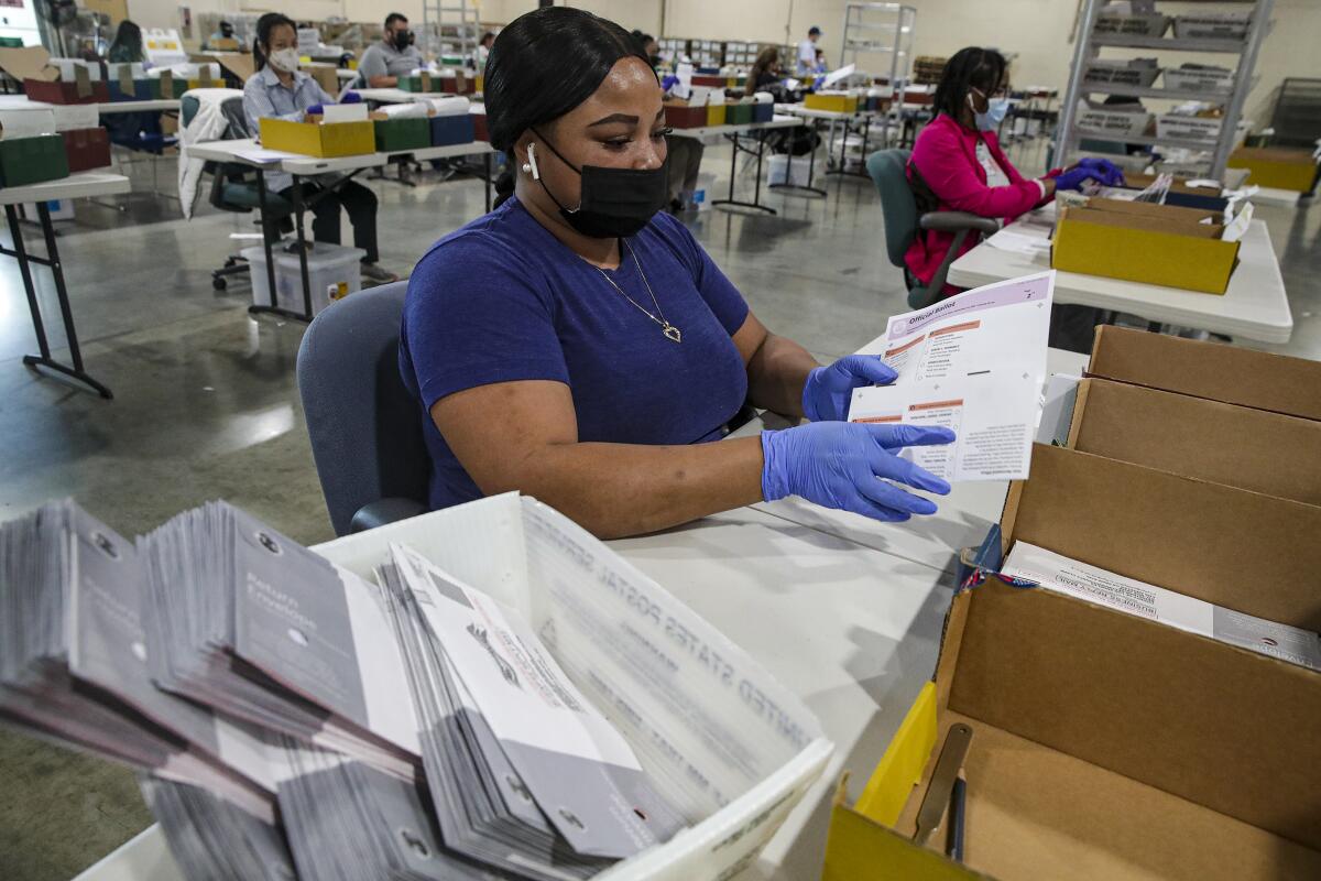 Election worker Tameka Augustus inspects a ballot that have been received for the Sept. 14, recall election