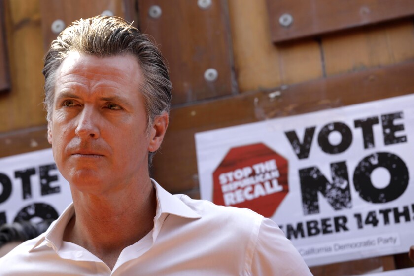 Gavin Newsom stands in front of a sign that says "Stop the Republican Recall"