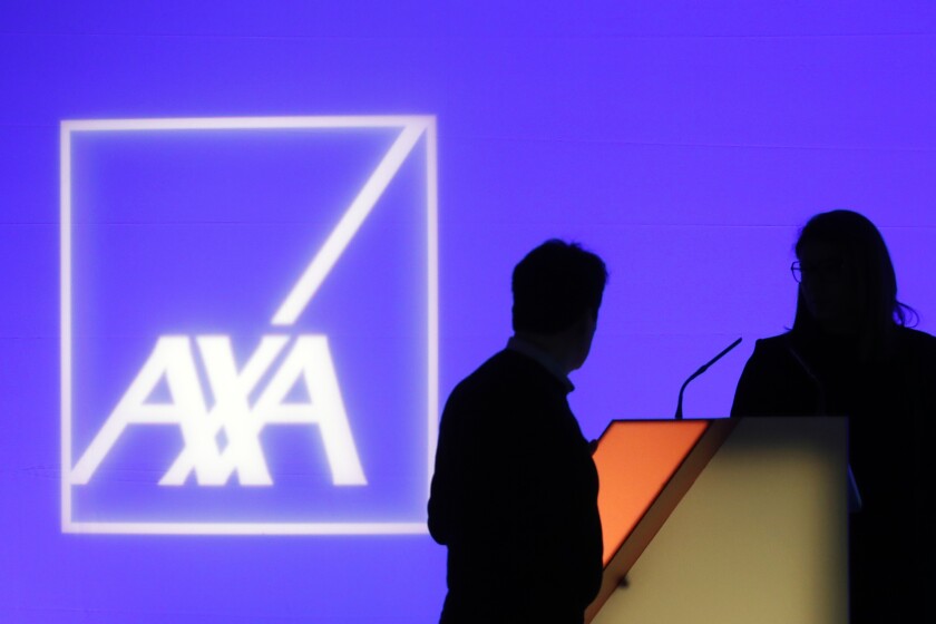 FILE - In this Feb. 21, 2019, file photo, people stand in front of the logo of AXA Group prior to the company's 2018 annual results presentation, in Paris. The cyber insurance industry, once a profitable niche, is now in the crosshairs of ransomware criminals. Pressure is building on the industry to stop reimbursing for ransoms, but so far only one major cyber insurer, AXA, is doing so — and only with new policies in France. To try to absorb the growing onslaught and stay profitable, insurers are retooling coverage, demanding clients up their security. (AP Photo/Thibault Camus, File)