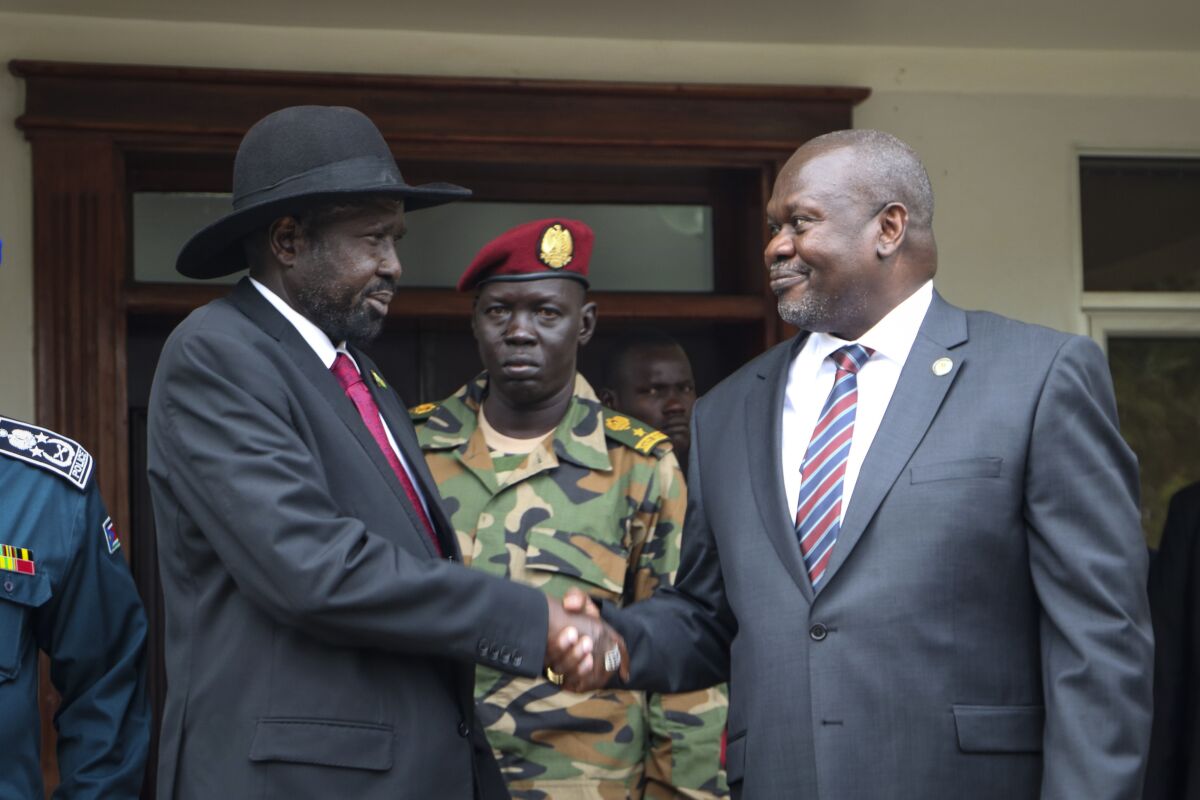 FILE - South Sudan's president Salva Kiir, left, and vice-president Riek Machar, right, shake hands after meetings to discuss outstanding issues to the peace deal on Oct. 20, 2019. Machar is urging regional mediators in March 2022 to intervene to protect the country's fragile peace deal, warning of a return to war amid alleged attacks by government troops on his forces.(AP Photo/Sam Mednick, File)