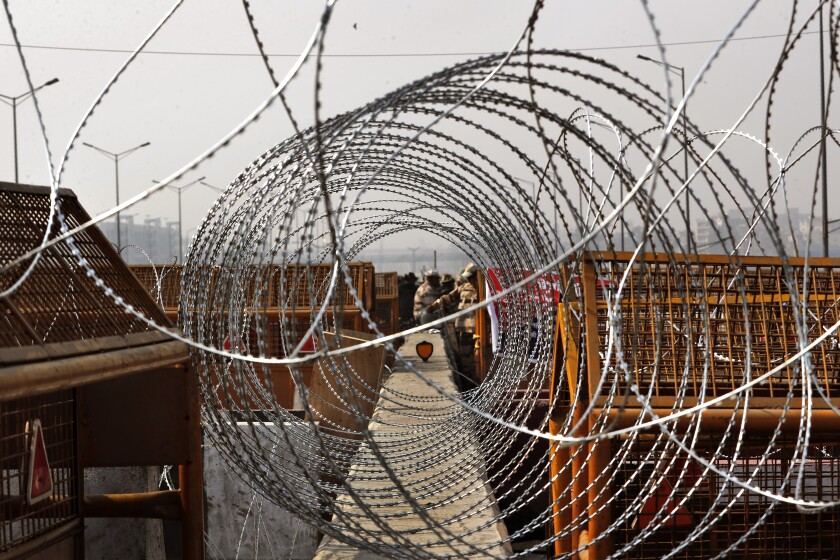 Indian para-military force soldiers stand against layers of barricades at Delhi-Utttar Pradesh border, in New Delhi, India, Tuesday, Feb. 2, 2021. Indian authorities Tuesday heavily ramped up security along three main protest sites outside New Delhi's border, using cemented iron spikes, steel barricades and deployed hundreds of police in riot gear in their latest attempt to thwart the growing farmers' protest on the edges of the capital. (AP Photo/Manish Swarup)