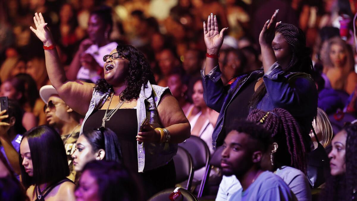The audience reacts as SZA performs.
