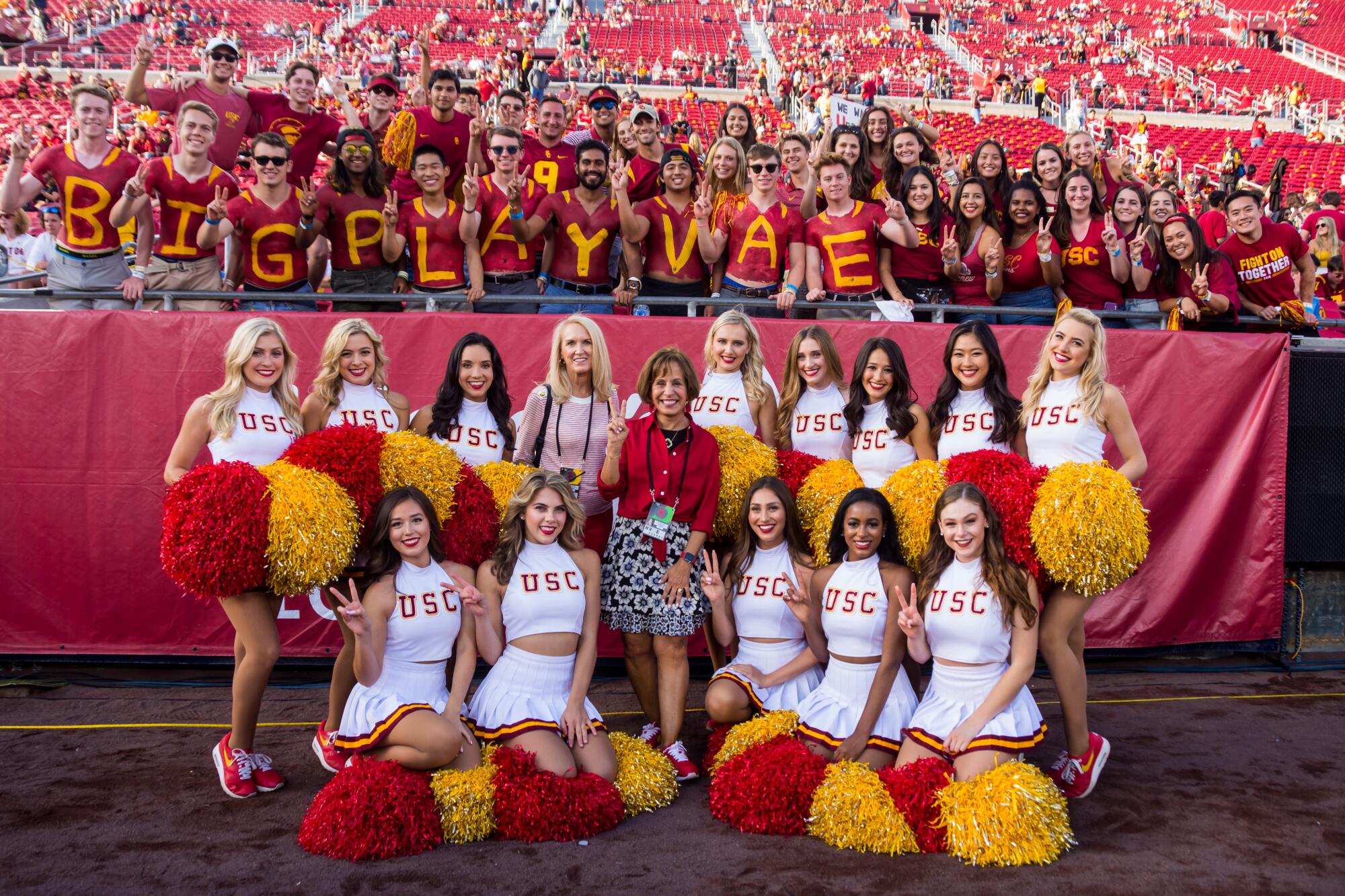 USC President Carol Folt (in red, center) poses with Lori Nelson (pink blouse) and the USC Song Girls.