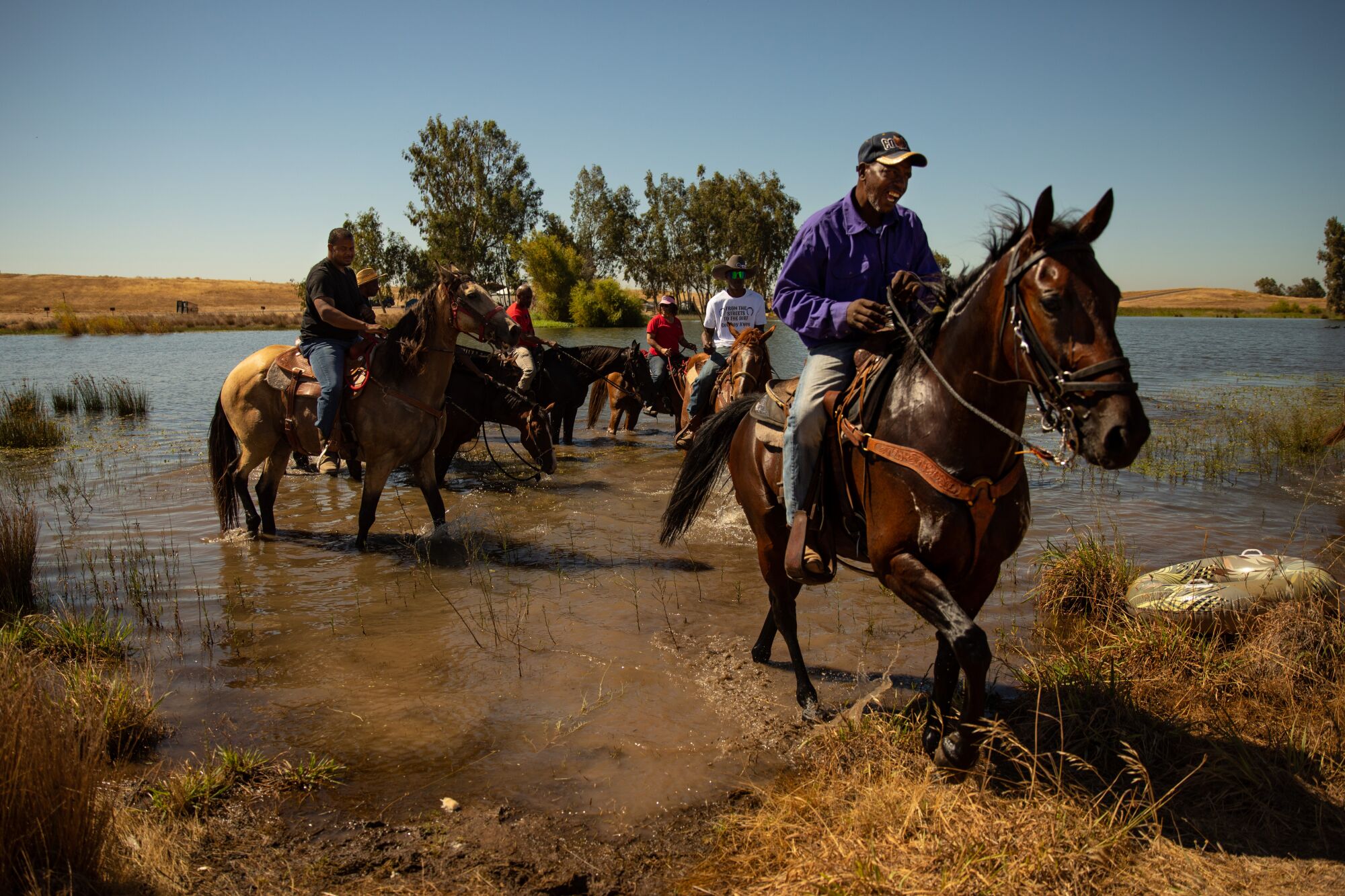 Several men on horses at the edge of a body of water