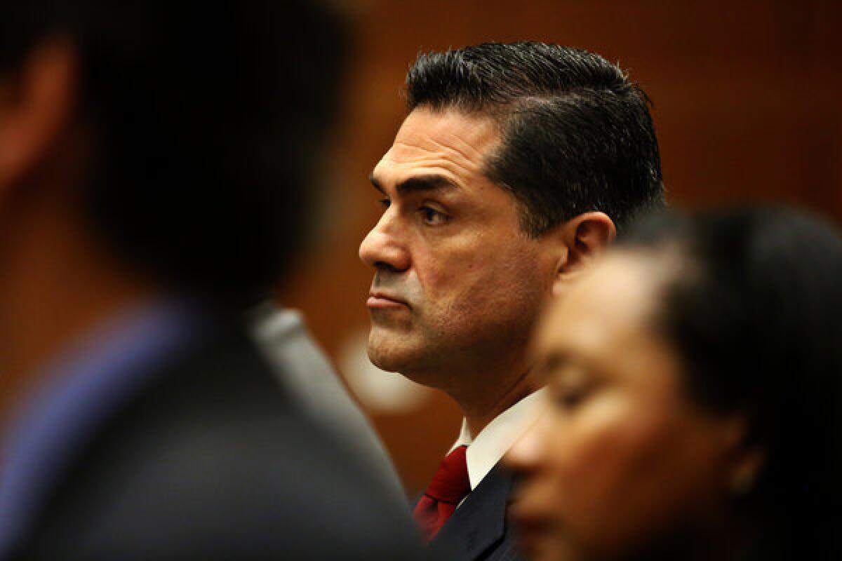L.A. County Assessor John Noguez, center, has been out on paid leave to prepare his defense.