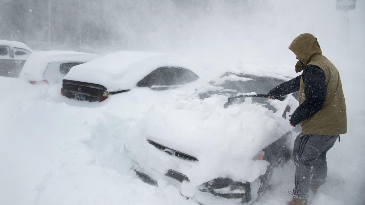 Ryan Foster, 25, scrapes snow from his car in the Donner Summit Lodge parking lot in Norden, Calif., on March 1.