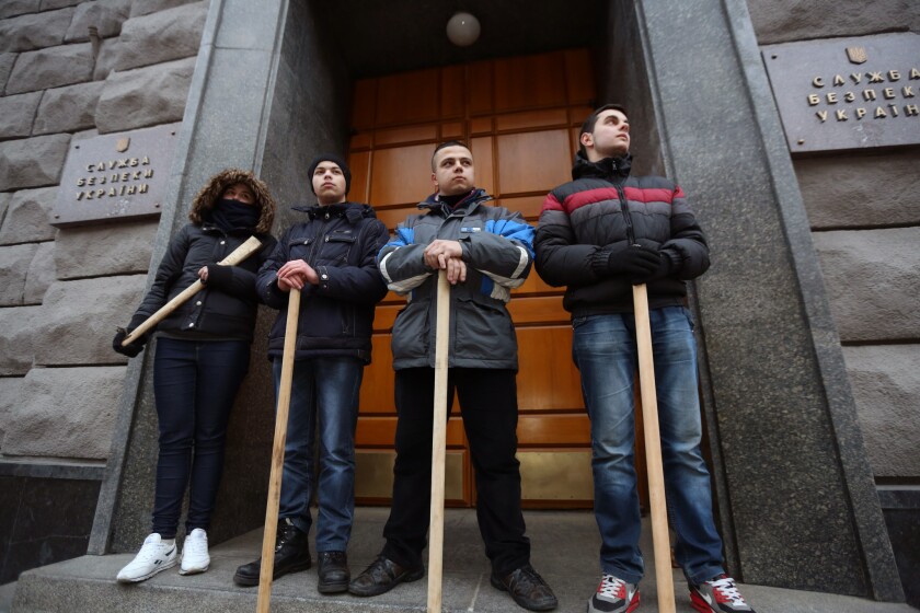 A group of young protesters armed with wooden sticks guard an entrance to the Security Service of Ukraine, the successor agency to the Ukrainian branch of the Soviet KGB, in Kiev on Tuesday.