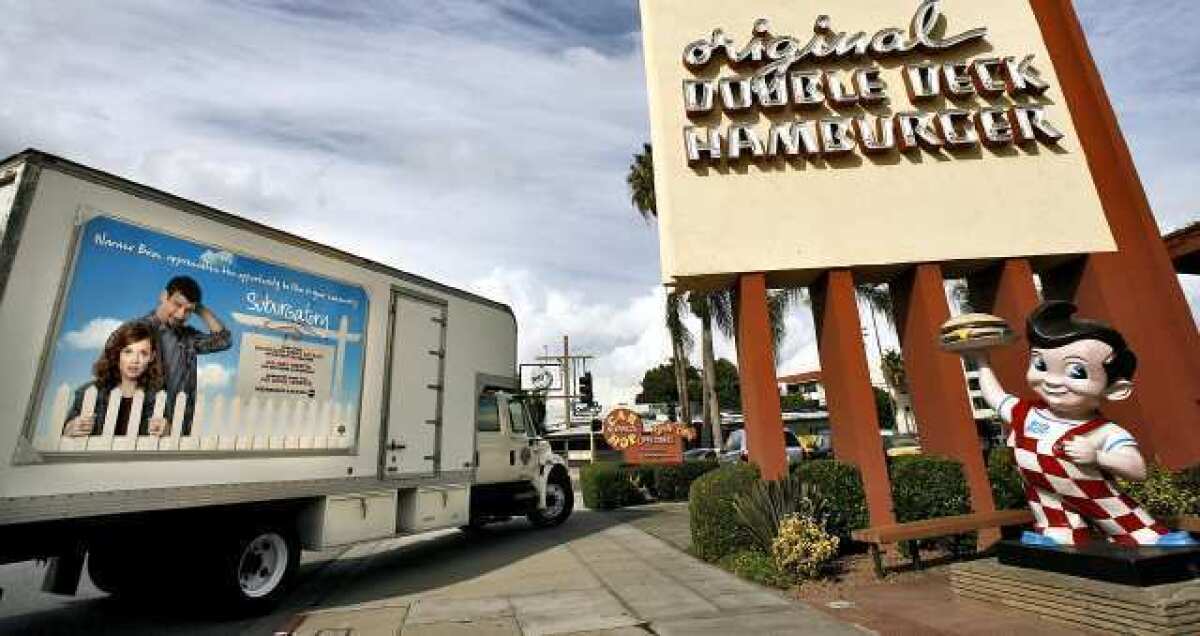 A Warner Bros. truck with advertising sign promoting how many jobs and other economic impacts the show "Suburgatory" has in the area enters the Bob's Big Boy driveway in Burbank.