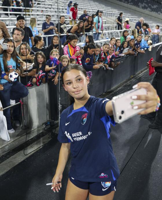 A woman takes a selfie with fans