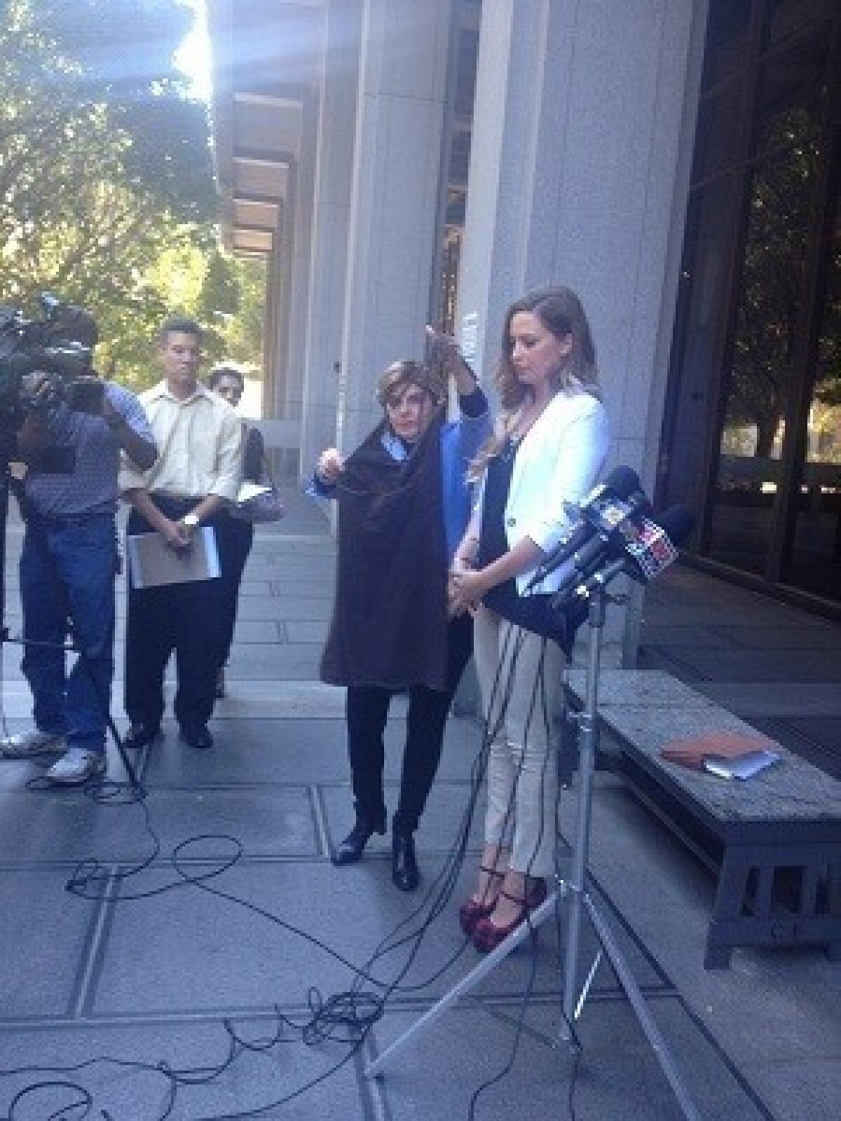 Model Brittanie Weaver, right, with attorney Gloria Allred, who is holding up the dress Weaver was wearing when video was secretly taken up her dress at a pet store.