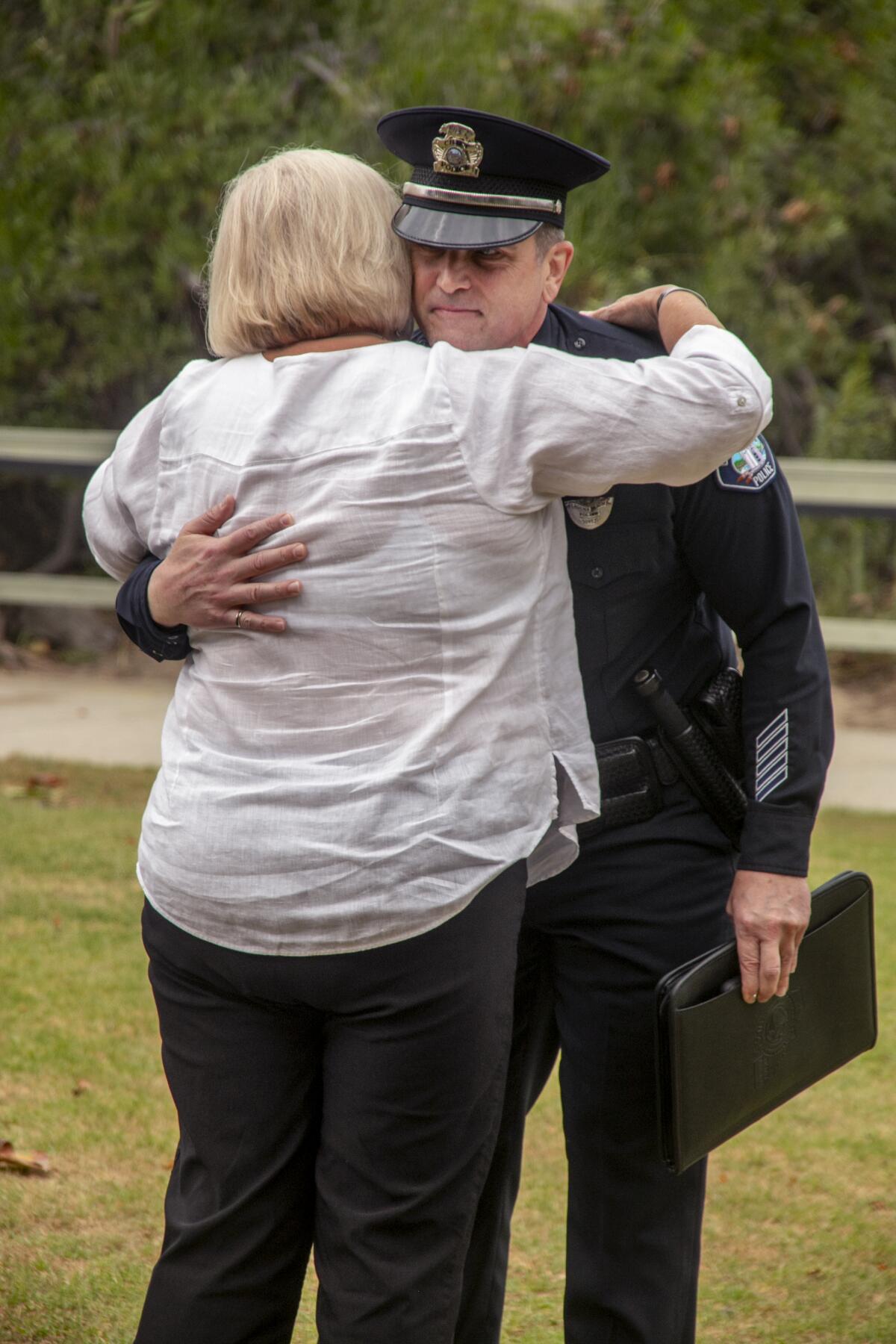 After his speech about her son, Laguna Beach Police Chief Jeff Calvert receives a hug from Officer Jon Coutchie's mother.