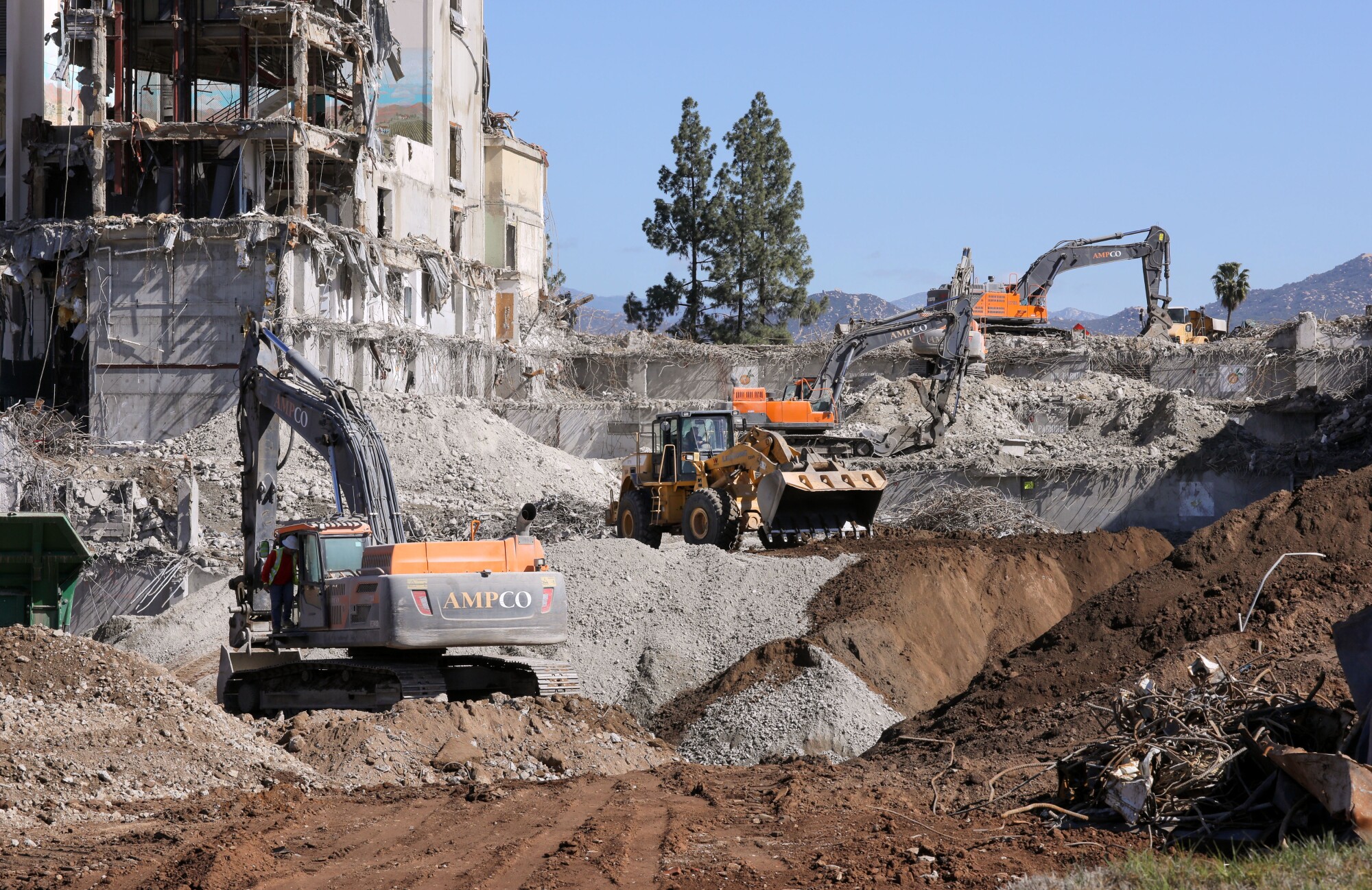 Demolition of the downtown Escondido Palomar Hospital continues. Heavy equipment works on its parking structure at right.