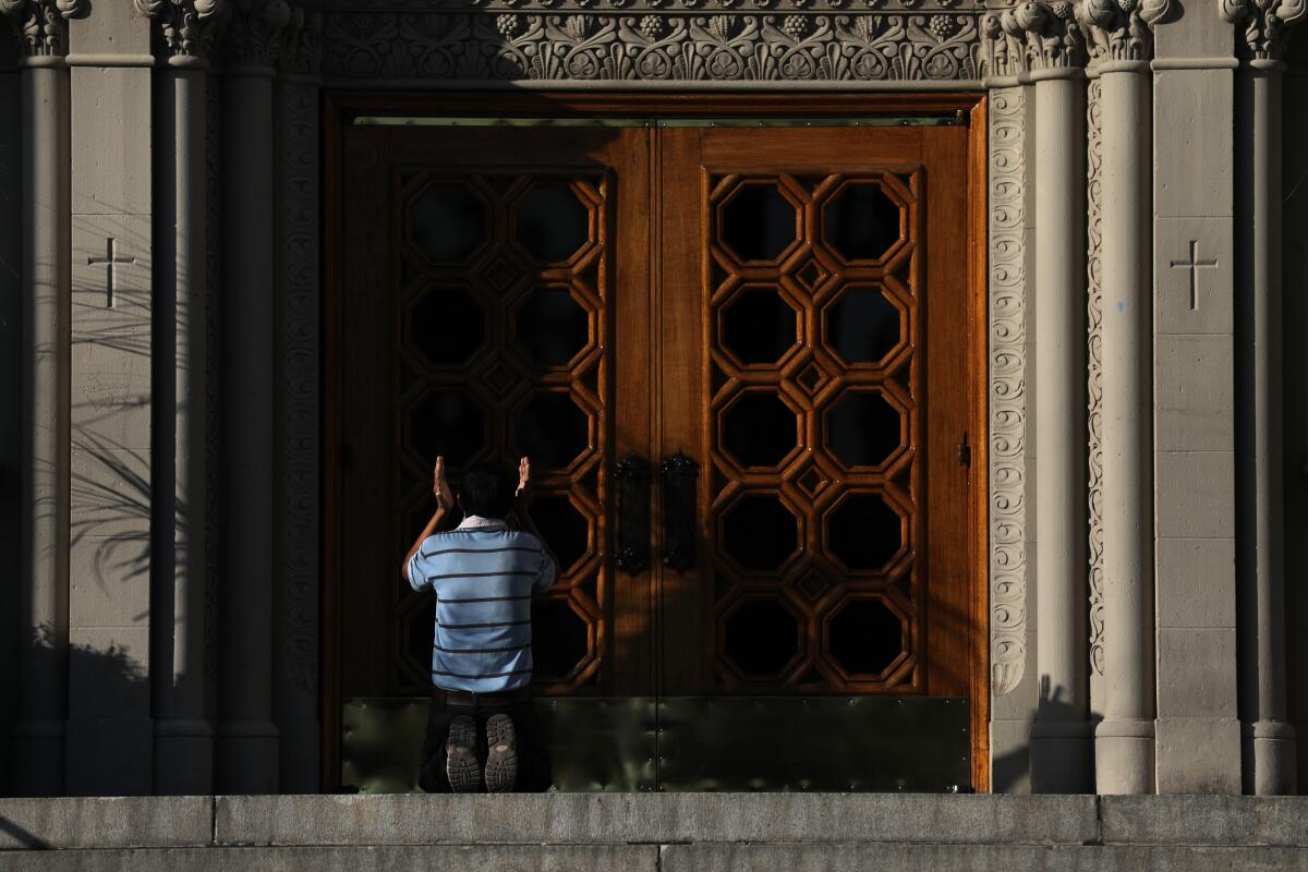 Francisco Lorenzo prays in front of the closed doors of the Immaculate Conception Catholic Church in downtown Los Angeles on April 21.