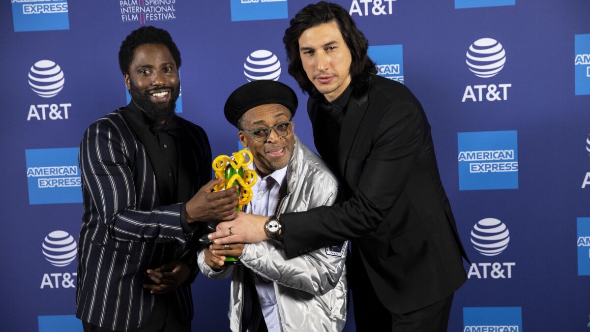 Director Spike Lee, center, with the Career Achievement Award presented to him by actors John David Washington, left, and Adam Driver.