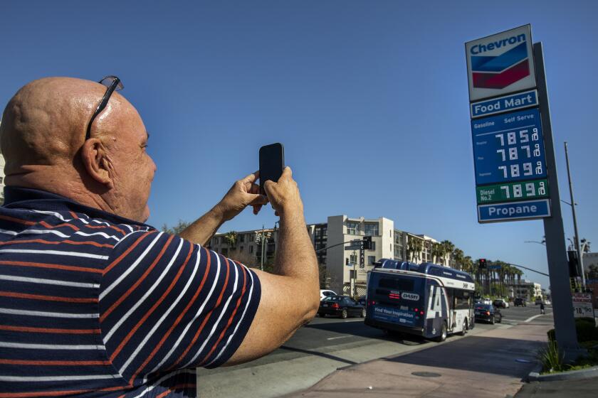 LOS ANGELES, CA-JUNE 1, 2022: Jim Moreno, 56, of Los Angeles, takes a photograph of the sign, showing the price of gasoline approaching close to $8 a gallon at the Chevron gas station located at the intersection of Cesar. E. Chavez Ave. and Alameda Street in downtown Los Angeles. (Mel Melcon / Los Angeles Times)