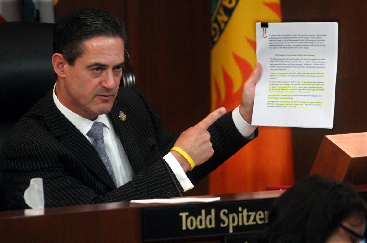 Orange County Supervisor Todd Spitzer holds up copy of a ruling by Superior Court Judge Marc Kelly.