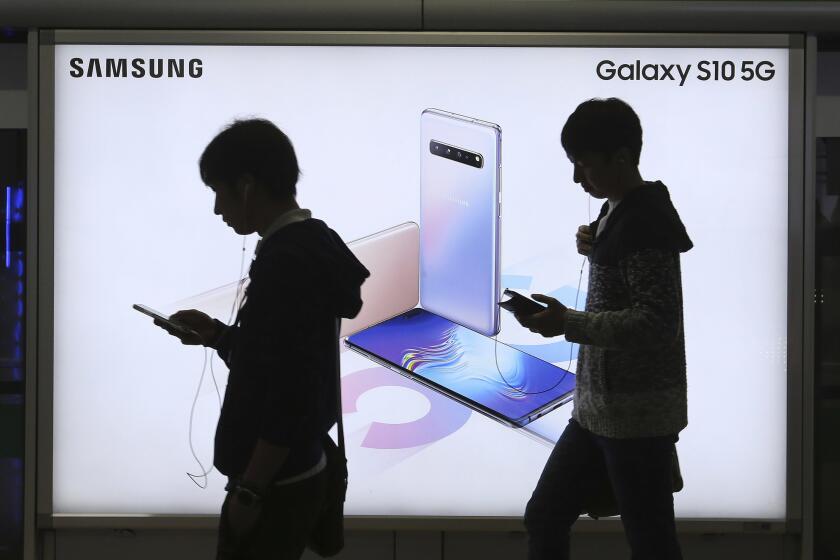 People pass by an advertisement of Samsung Electronics' Galaxy S10 5G smartphone at a subway station in Seoul, South Korea, Tuesday, April 30, 2019. Samsung Electronics Co. says its operating profit for the last quarter declined more than 60% from a year earlier because of falling chip prices and sluggish demands for its display panels. (AP Photo/Ahn Young-joon)