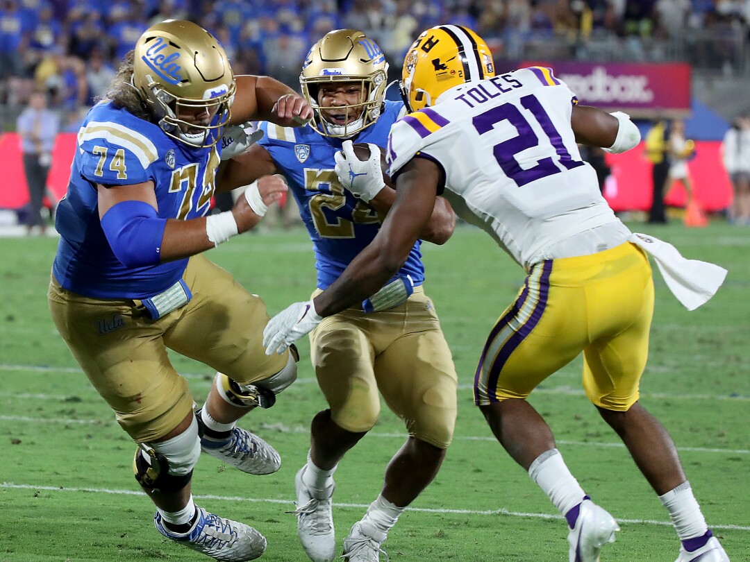 UCLA's running back, Zach Charbonnet, follows a block by teammate Sean Rhyan.