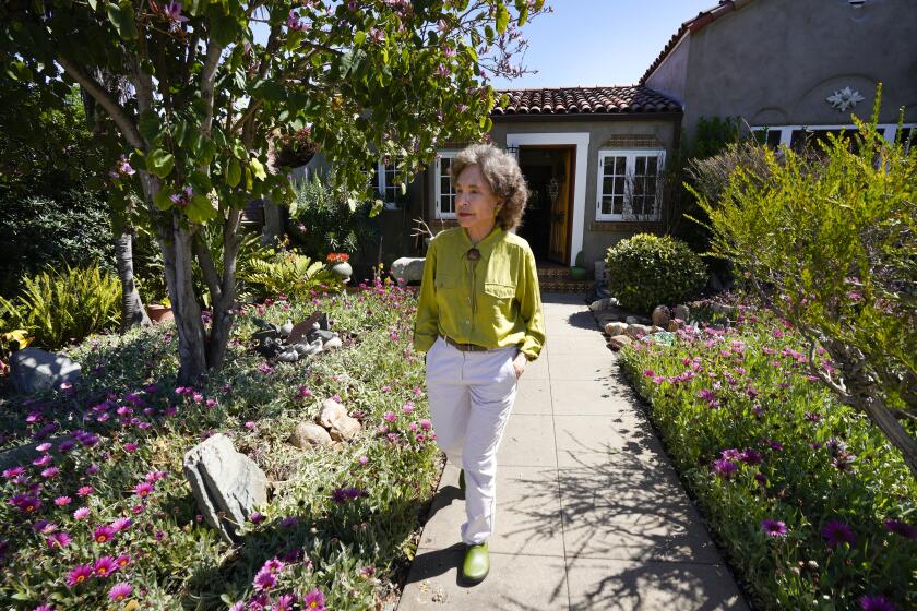 A woman points out the variety of plants and trees she has added over the years in her front yard.