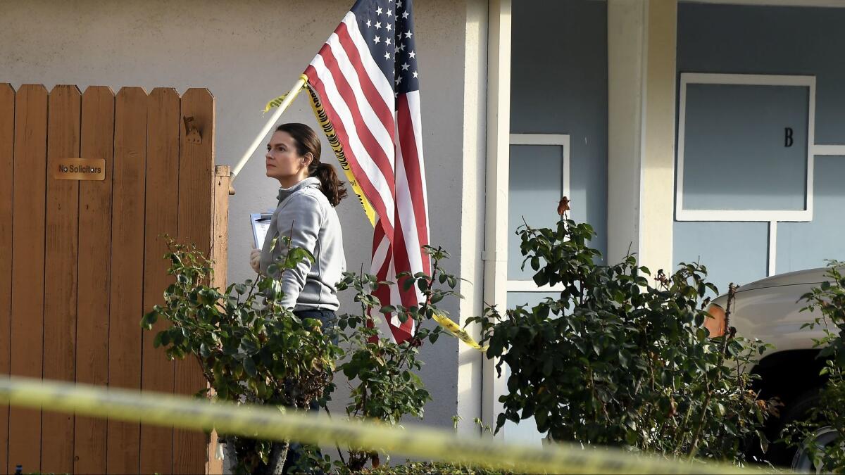 An investigator searches for evidence at the home of a retired L.A. County sheriff's deputy who was shot Thursday morning while answering his door.