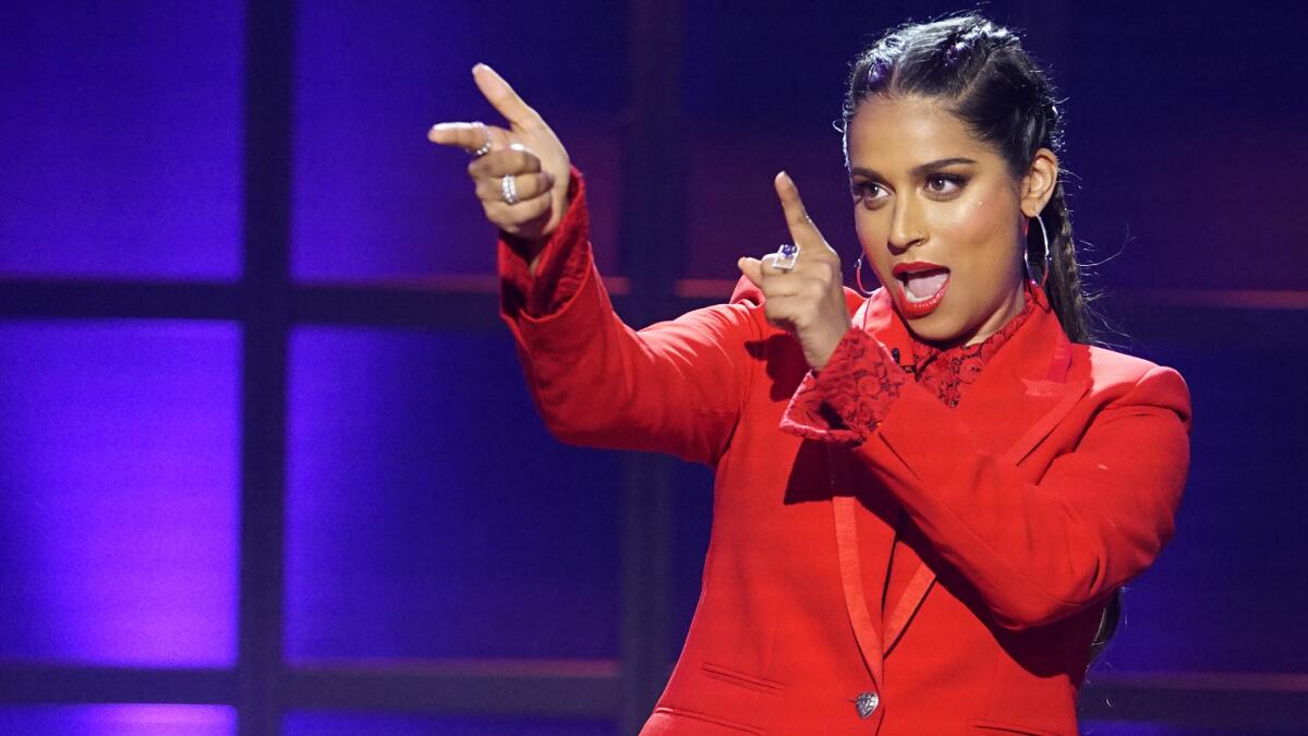 A woman in a red suit points finger guns off camera.