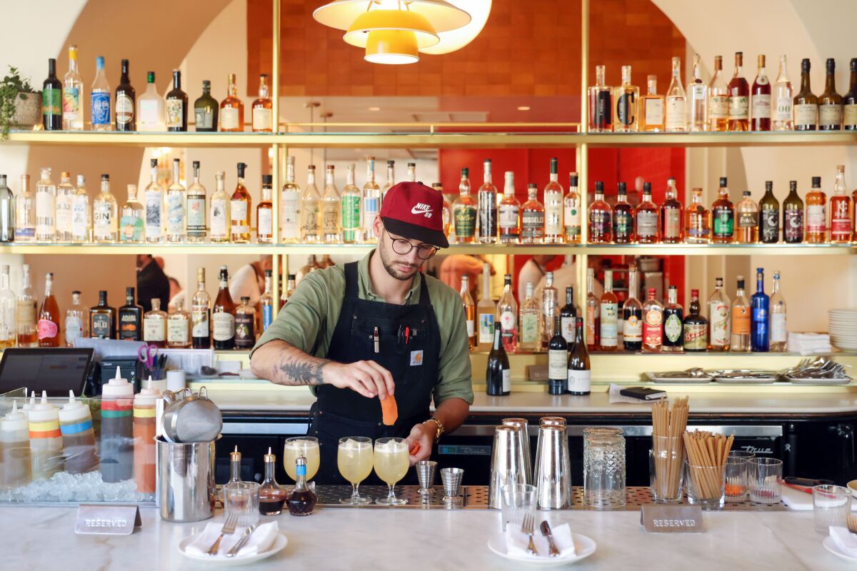 A bartender prepares cocktails at a bar.