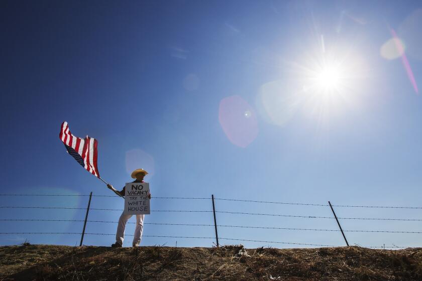 Protester William Satmary of Murrieta stands on a hill to keep a lookout for buses containing immigrant detainees.