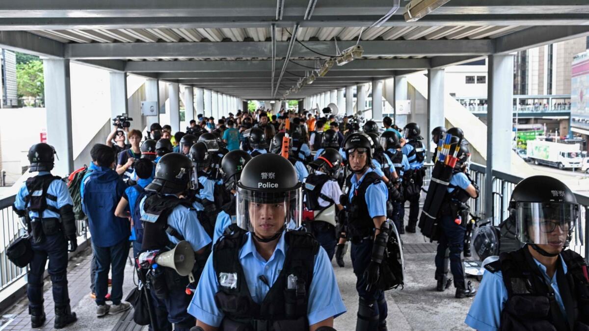 Police in Hong Kong guard a footbridge early Thursday after a violent demonstration against a controversial extradition law proposal.
