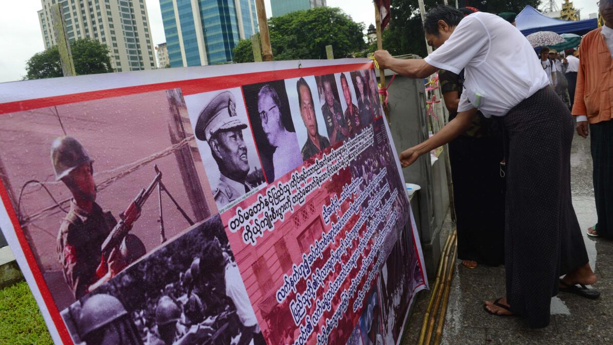 An activist displays a banner bearing portraits of military junta leaders at a Yangon rally to mark the 28th anniversary of the Aug. 8, 1988, democracy uprising.