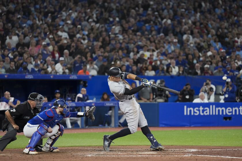 New York Yankees' Aaron Judge hits a two-run home run, his 61st homer of the season, next to Toronto Blue Jays catcher Danny Jansen during the seventh inning of a baseball game Wednesday, Sept. 28, 2022, in Toronto. (Nathan Denette/The Canadian Press via AP)