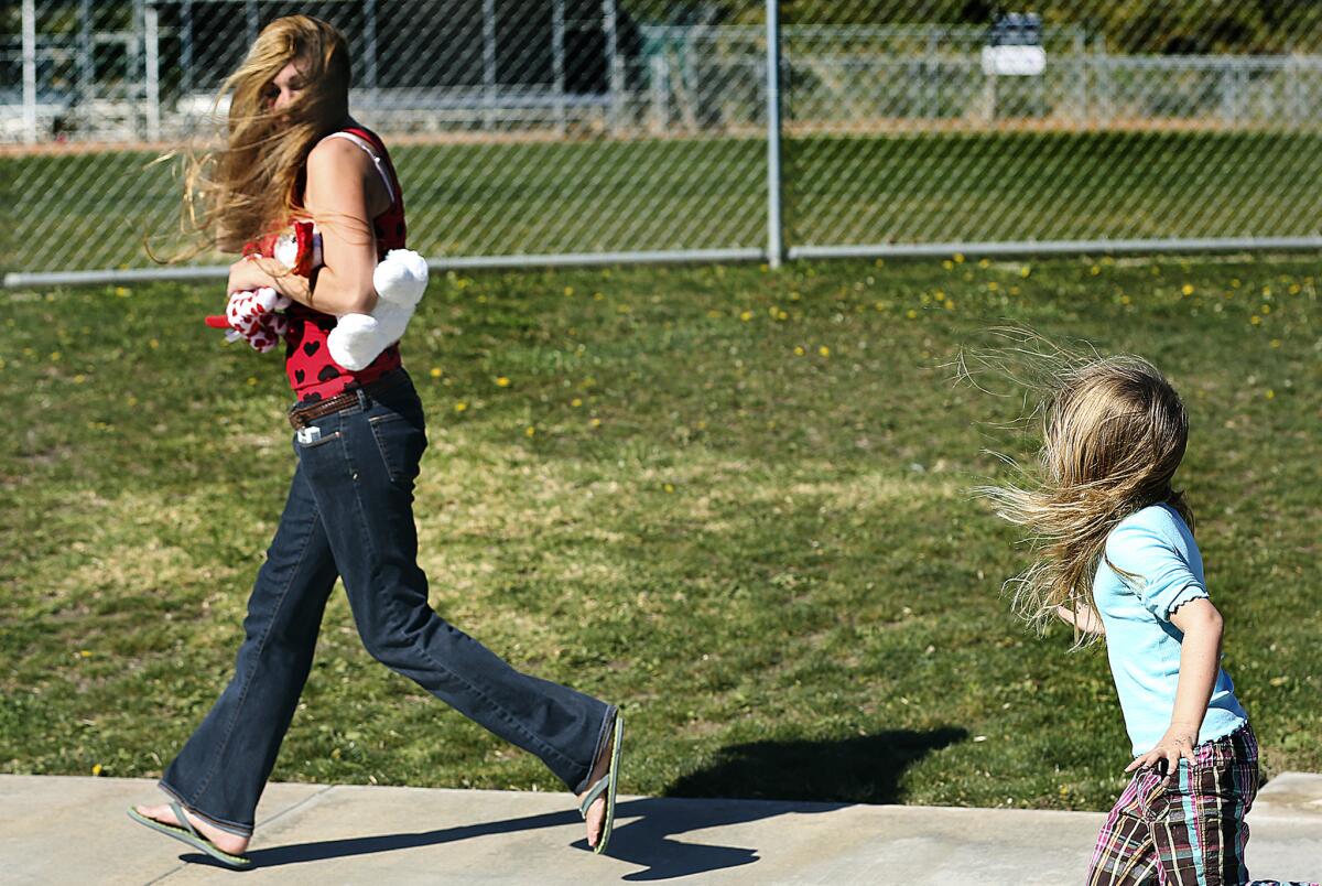 In this file photo, a woman and her daughter run in the wind in Simi Valley. Powerful winds will slam into Los Angeles late this week following the rain-filled weekend.