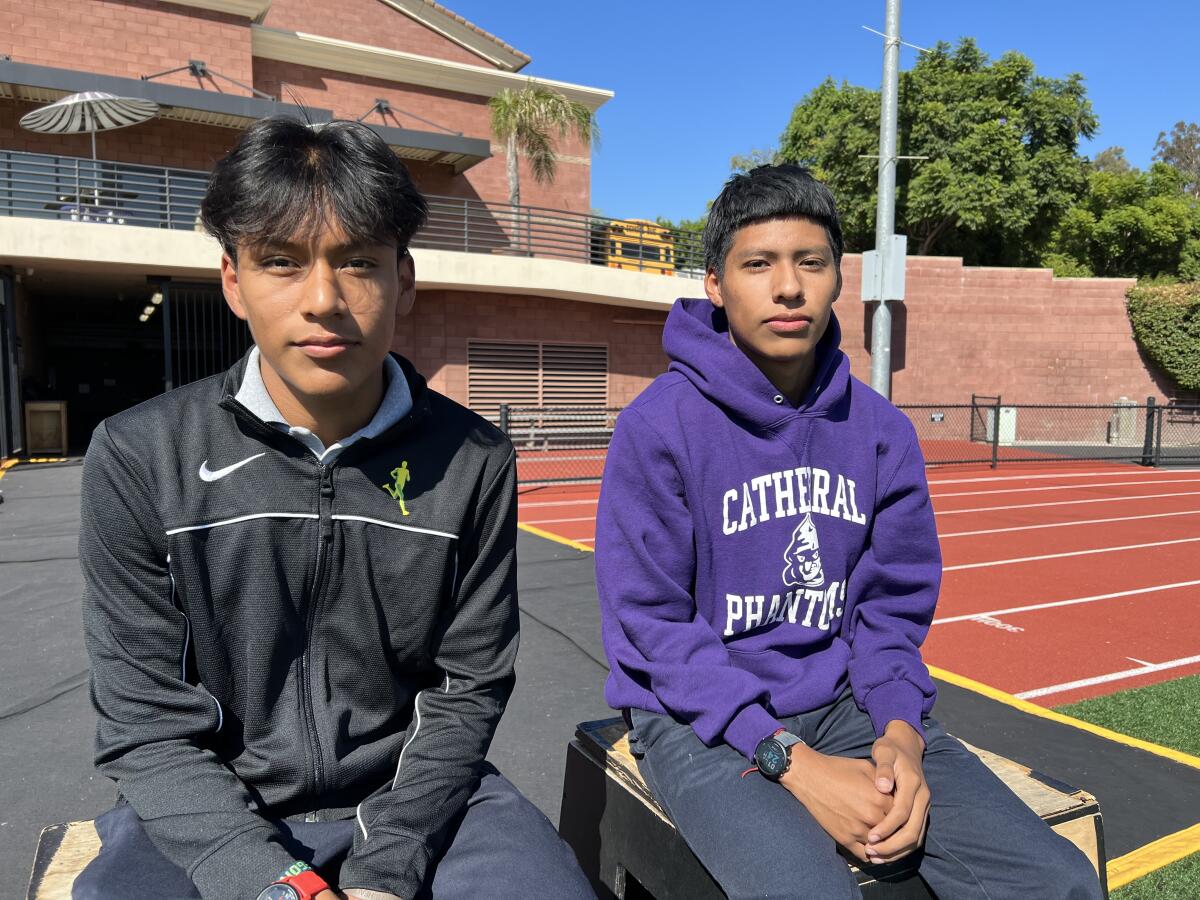 Two teenage boys sit next to a running track