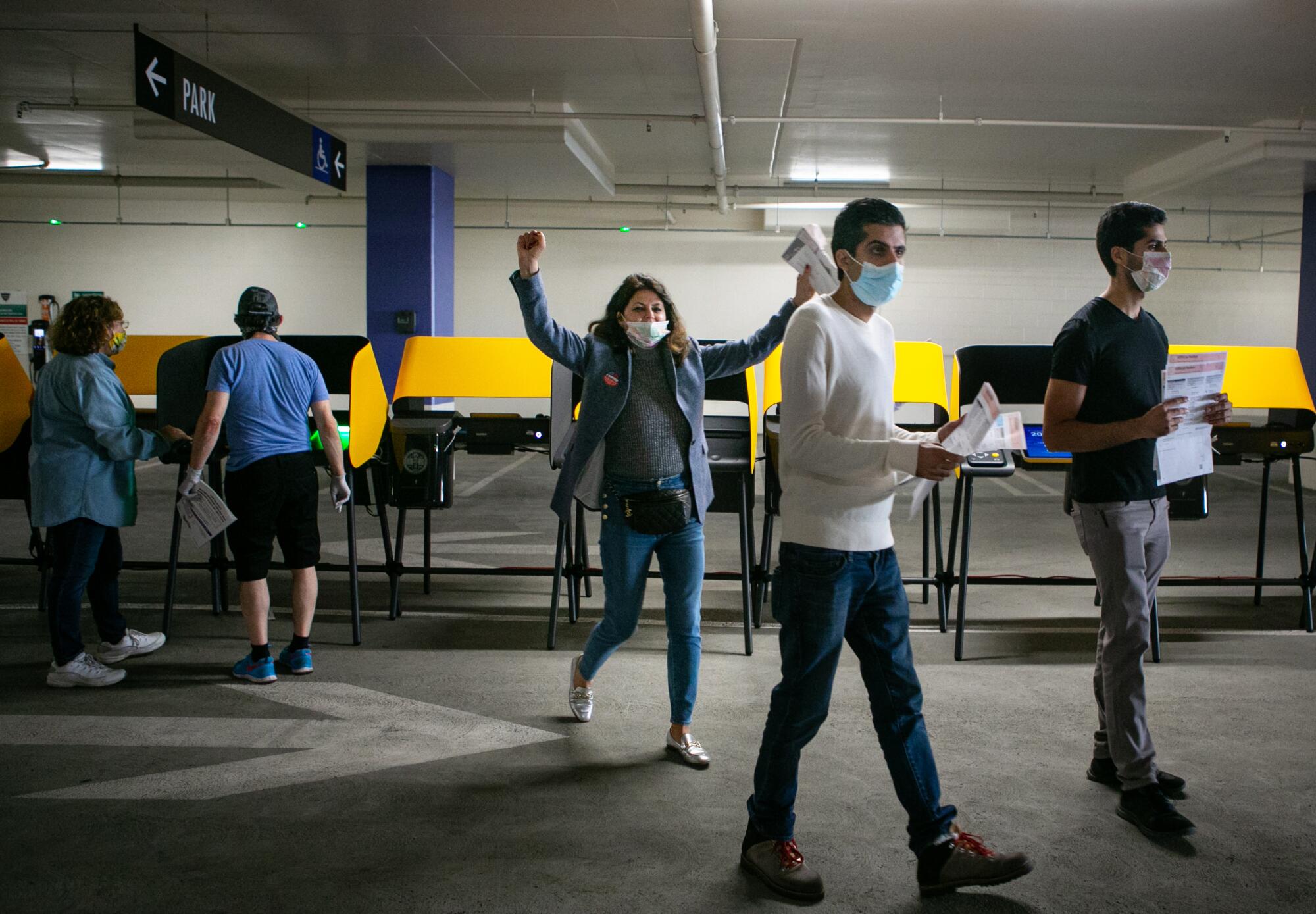 A women raises her arms in celebration after casting her ballot at the Beverly Hills City Hall parking garage.