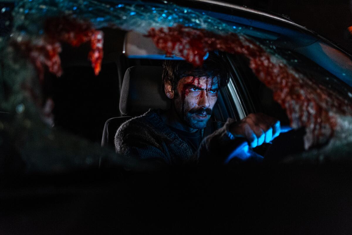 A man sits in a bloody car.