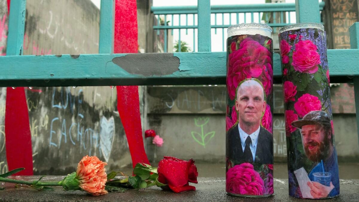 Candles bearing photos of two stabbing victims sit at a memorial in Portland. A photo of Ricky Best, 53, is on the left, and that of Taliesin Myrddin Namkai Meche, 23, is on the right.