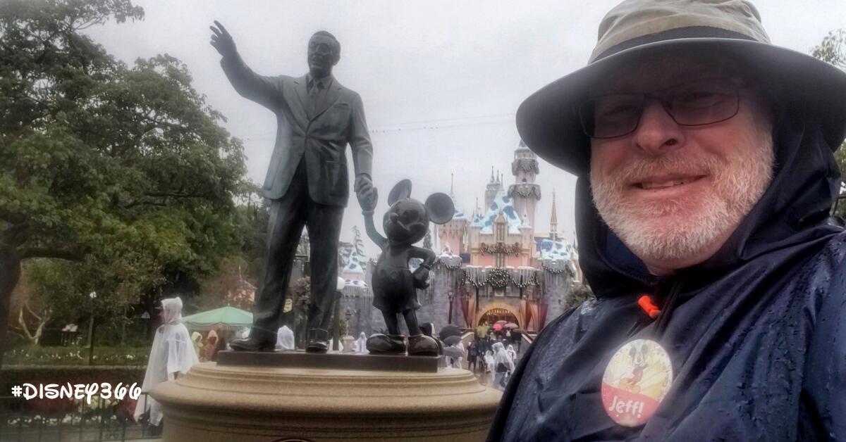 Jeff Reitz stands near a statue of Walt Disney holding hands with Mickey Mouse.