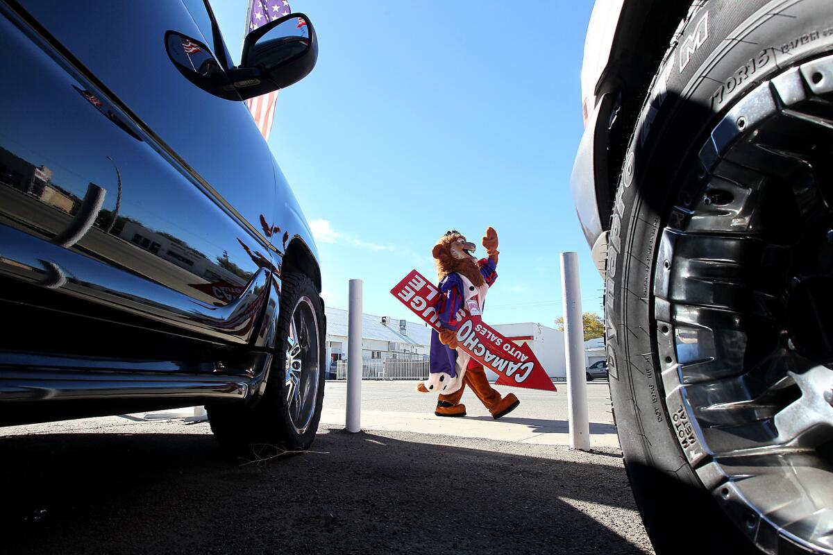 Camacho Auto Sales' mascot, a lion known as "The King of Credit," waves at traffic on Sierra Highway in Lancaster.