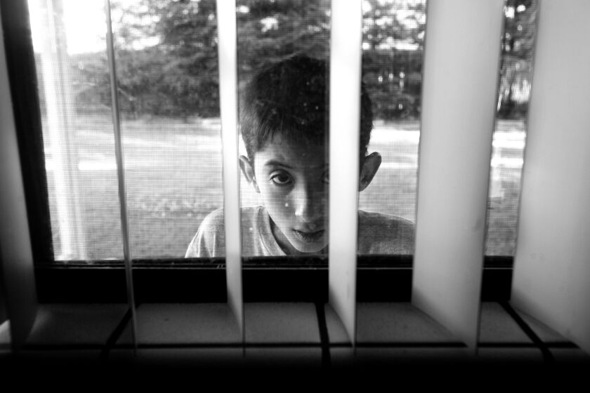 Joseph Gutierrez, 13, peeks into the kitchen window as he paces in the back yard in Sanger, CA.
