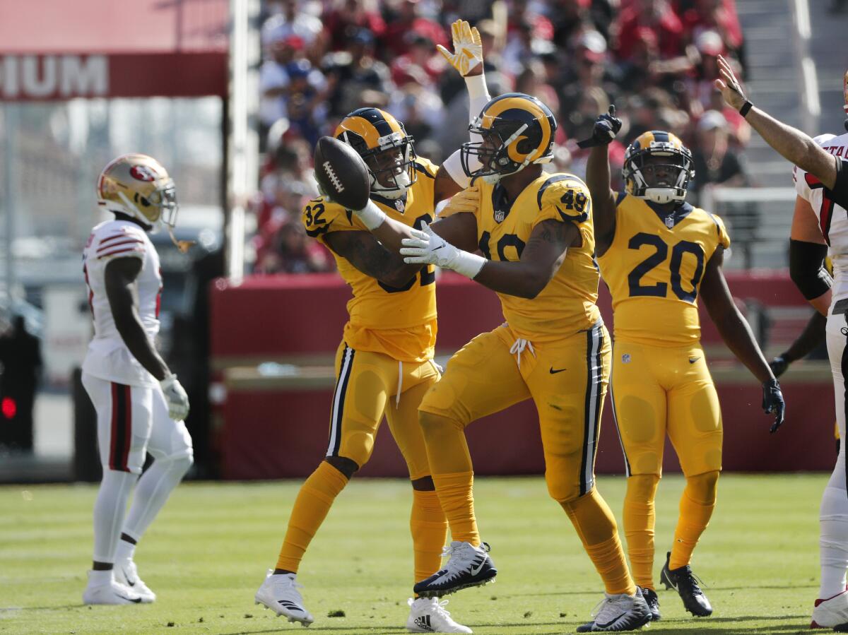 Rams linebacker Trevon Young (49) celebrates with teammates Troy Hill (32) and Lamarcus Joyner (20) after intercepting a pass against the San Francisco 49ers last season.