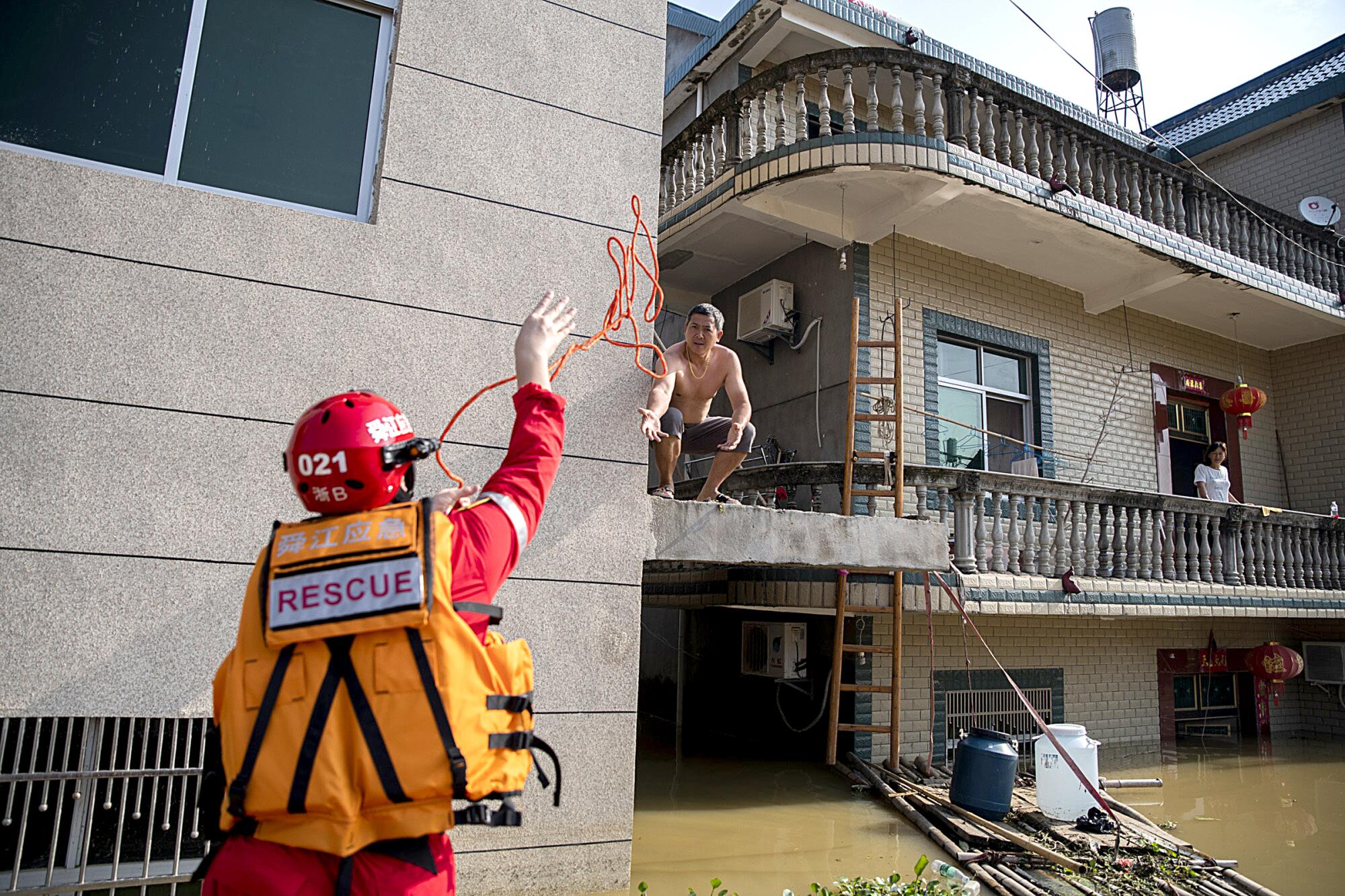 A rescue volunteer throws a rope to a resident in Poyang.