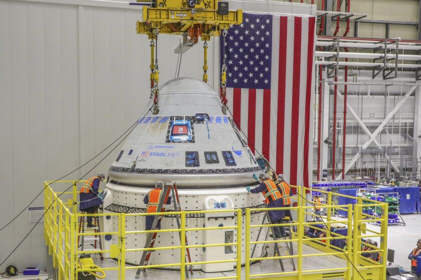 In this photo provided by Boeing, technicians work on the Starliner spacecraft at the Kennedy Space Center in Florida on Jan. 19, 2023, in preparation for NASA's Boeing Crew Flight Test. On Wednesday, March, 29, 2023, NASA said Boeing's debut launch of astronauts has been delayed again, this time until July, saying more time is needed to certify the rocket and capsule that will blast off with the two test pilots. (John Grant/Boeing via AP)