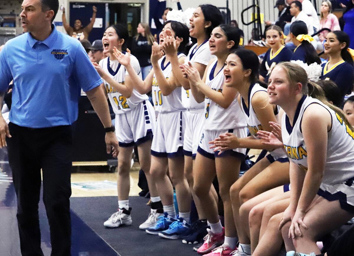 Marina girls' basketball players cheer for their teammates after a basket against Huntington Beach on Monday.