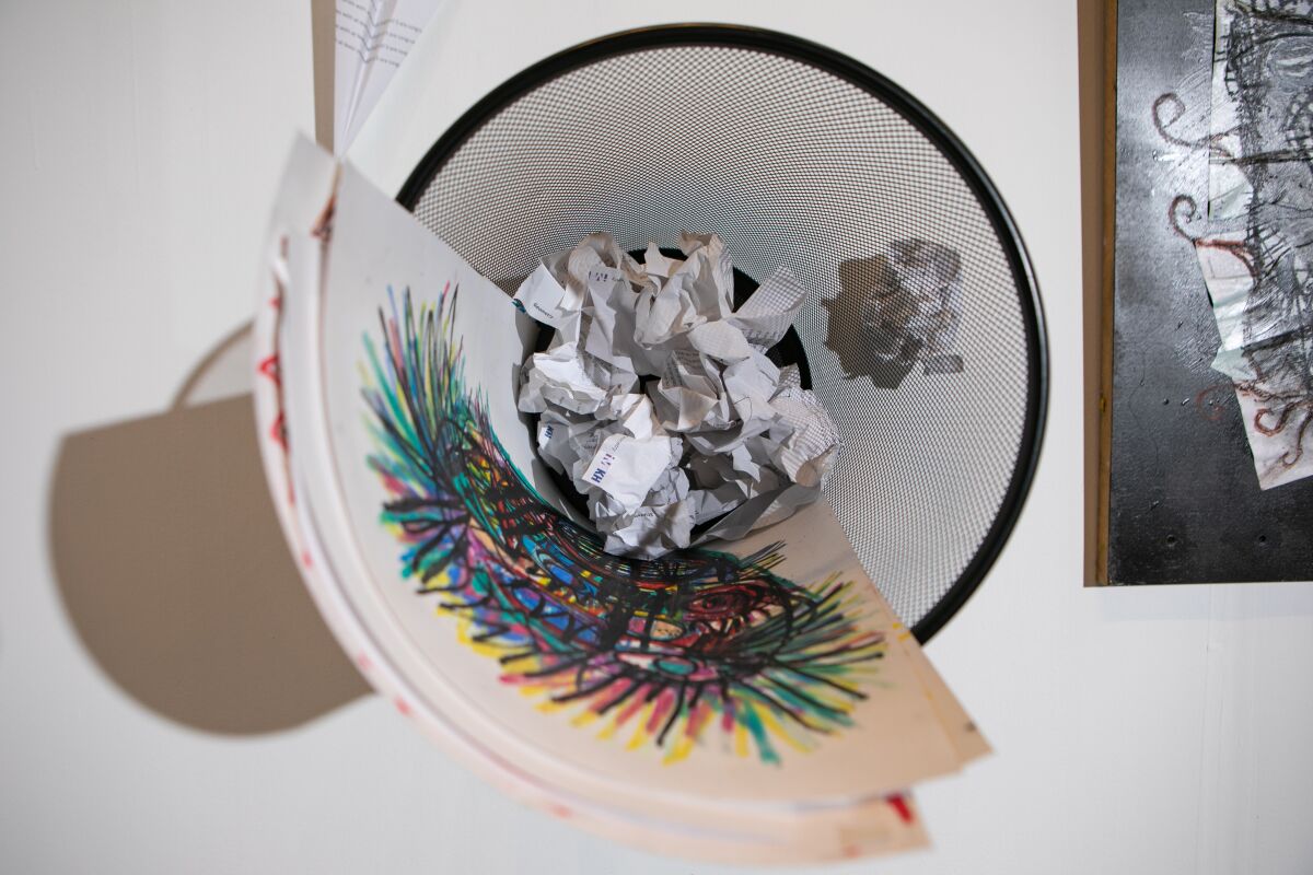 Colorful drawings and crumpled paper in a trashcan, seen from above.