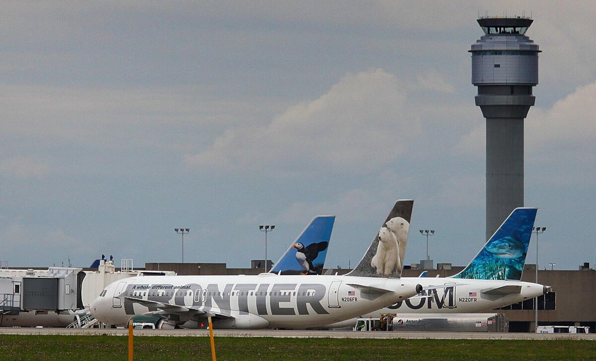 A Frontier Airlines plane is parked at a gate at Cleveland Hopkins Airport on Wednesday. Union leaders for flight attendants and pilots are calling for better communications and coordination to reduce the risk of further Ebola outbreaks.