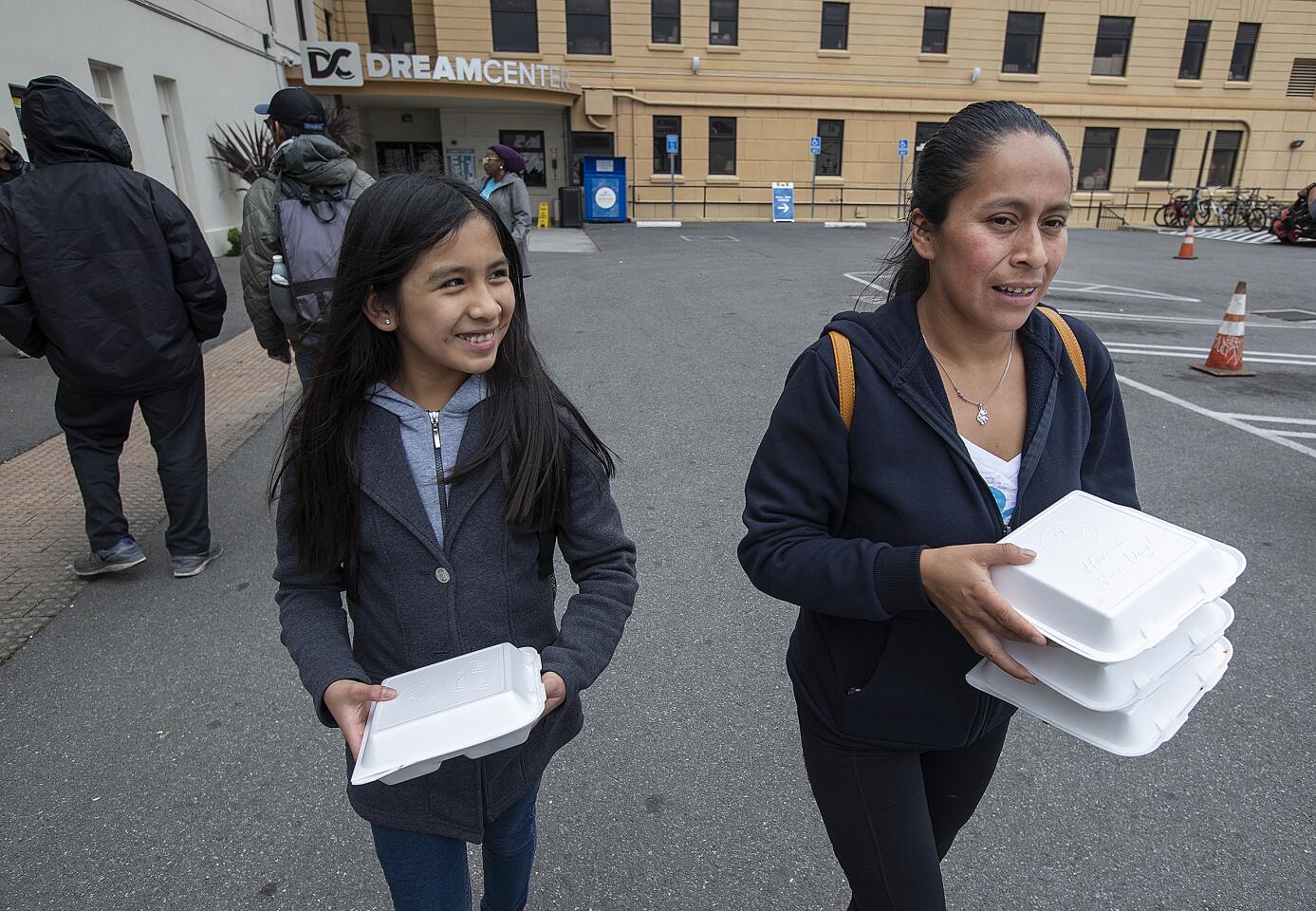 Karyna Renoj, 11, and her mom, Pascuala Reno, carry box lunches.