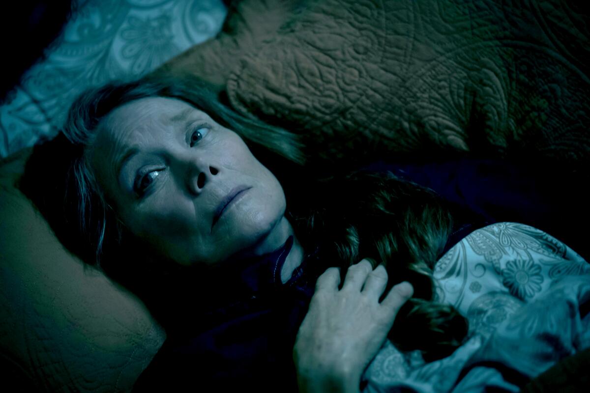 A woman lays on her bed at night.