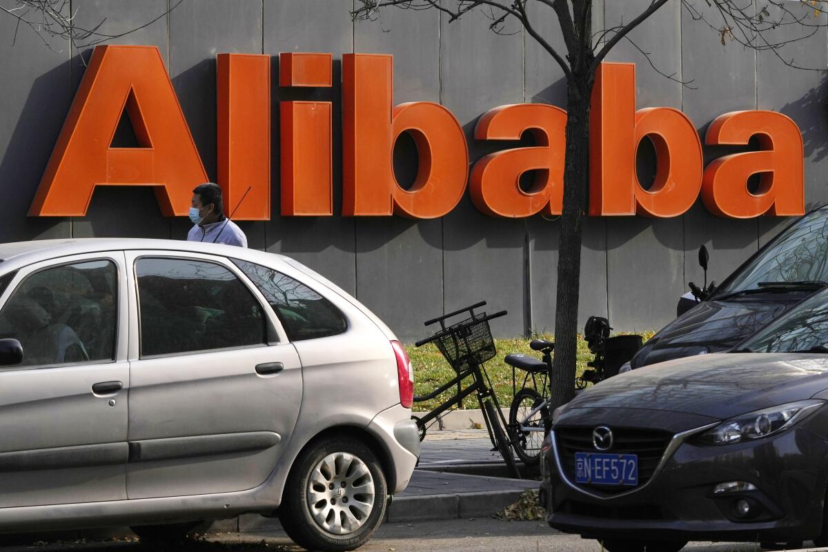 FILE - The Alibaba logo is seen outside a building in Beijing on Nov. 16, 2021. Chinese e-commerce giant Alibaba said in a statement Monday, Dec. 6, 2021, that it is replacing its CFO and restructuring its business as the company weathers a multifaceted crackdown on the industry. (AP Photo/Ng Han Guan, File)