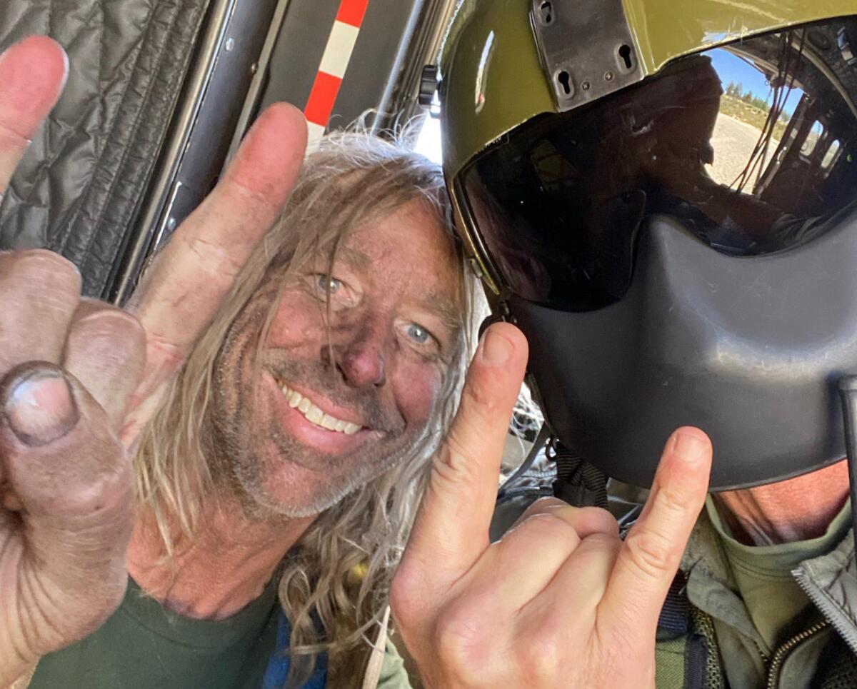 George Null and a helmeted helicopter crew member flash "rock on" hand signs.